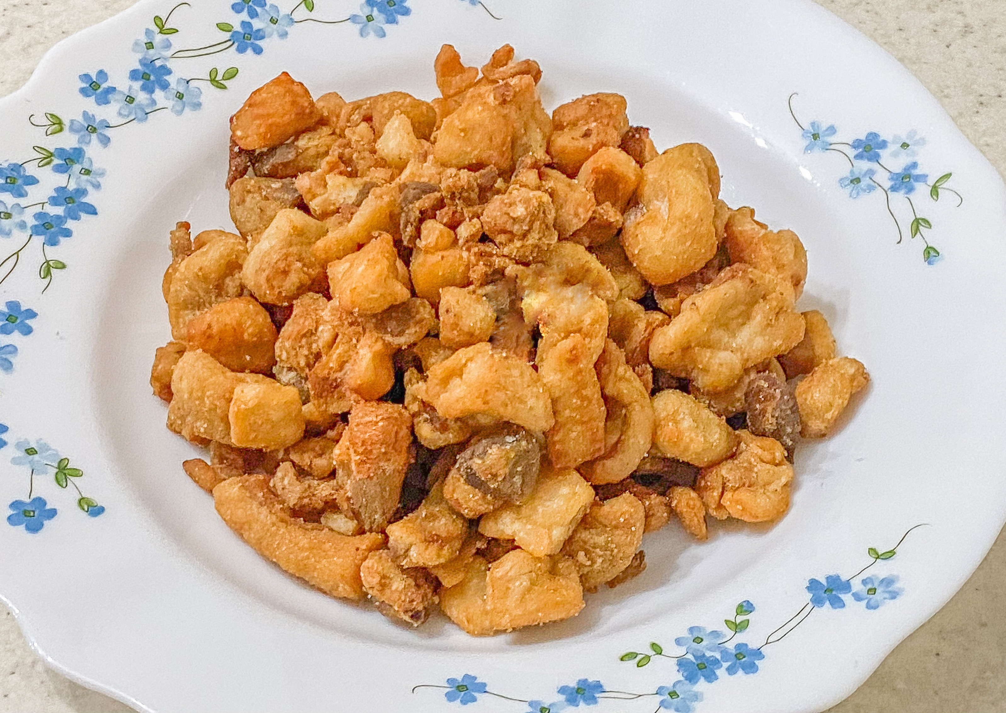 Kafana-style kajmak — crispy pieces on a floral plate